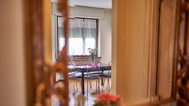 Un coin repas avec une table et des chaises, une fenêtre avec des rideaux et un vase rempli de fleurs.