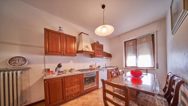 Une cuisine avec des meubles de rangement en bois, une cuisinière, un évier et une table à manger avec des chaises.