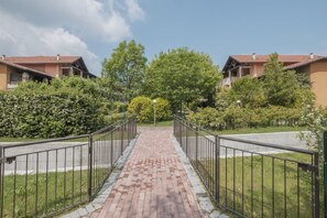 A pathway leading to a row of buildings with a brick-paved walkway and metal railings.