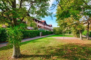 A building with a red roof and arched windows, surrounded by a well-maintained lawn and trees.