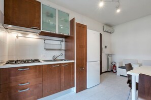 A modern kitchen with wooden cabinets, a gas stove, a sink, and a white refrigerator.