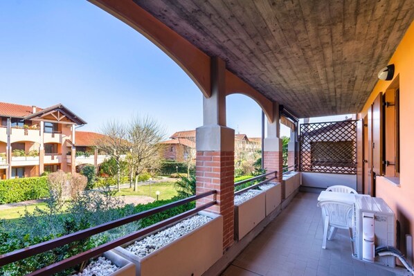 Ein Balkon mit Blick auf einen Innenhof, ein Tisch mit Stühlen und eine kleine Gartenanlage.