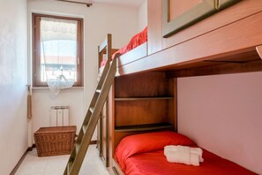 A bunk bed room with a window, a wicker basket, and a radiator.