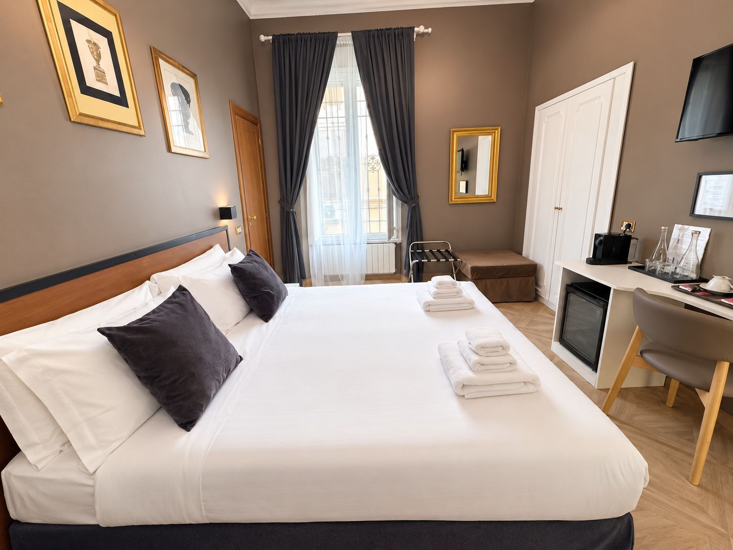 Ett hotellrum med en stor säng, ett skrivbord med en dator, en stol och en tv.