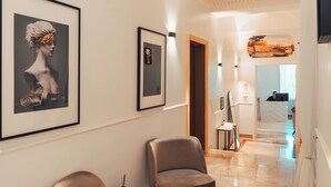 Un couloir orné de tableaux encadrés, un comptoir d’accueil et un sol en marbre.
