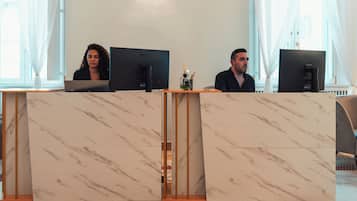 Una recepción con dos monitores LG, un florero con difusor de aroma de caña y una pared con diseño de mármol.