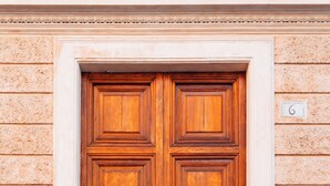Une porte en bois à deux battants, avec un seuil en métal et le chiffre « 6 » peint sur le mur.