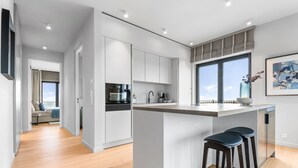 A modern kitchen with a central island, built-in appliances, and a large window. - Penthouse Suite with Sea View, Balcony, and Fireplace (List auf Sylt)