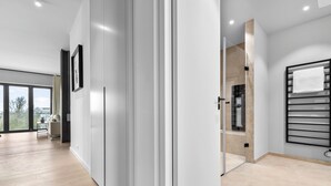 A modern interior with a large sliding door leading to a balcony, a minimalist bathroom with a towel rack, and a clean, light-colored floor. - Penthouse Suite with Sea View, Balcony, and Fireplace (List auf Sylt)