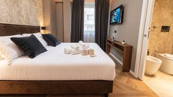 A hotel room with a large bed, a TV, a bathroom, and a view of the city.