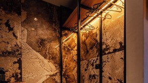 A modern bathroom with a wooden vanity, a marble wall, and a built-in bench with hooks. - Whim Collection Trastevere (Rome)