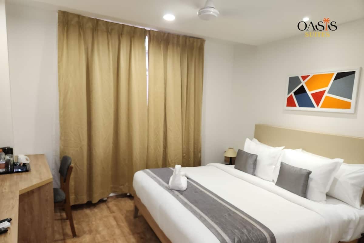 A hotel room with a bed, a desk, a chair, a lamp, and a painting on the wall.