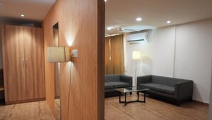 A modern living room with a sofa, a coffee table, and a lamp. - OASIS SUITES (Hubli)