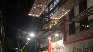 A hotel entrance with a modern design, featuring a glass facade and a red and white color scheme. - OASIS SUITES (Hubli)