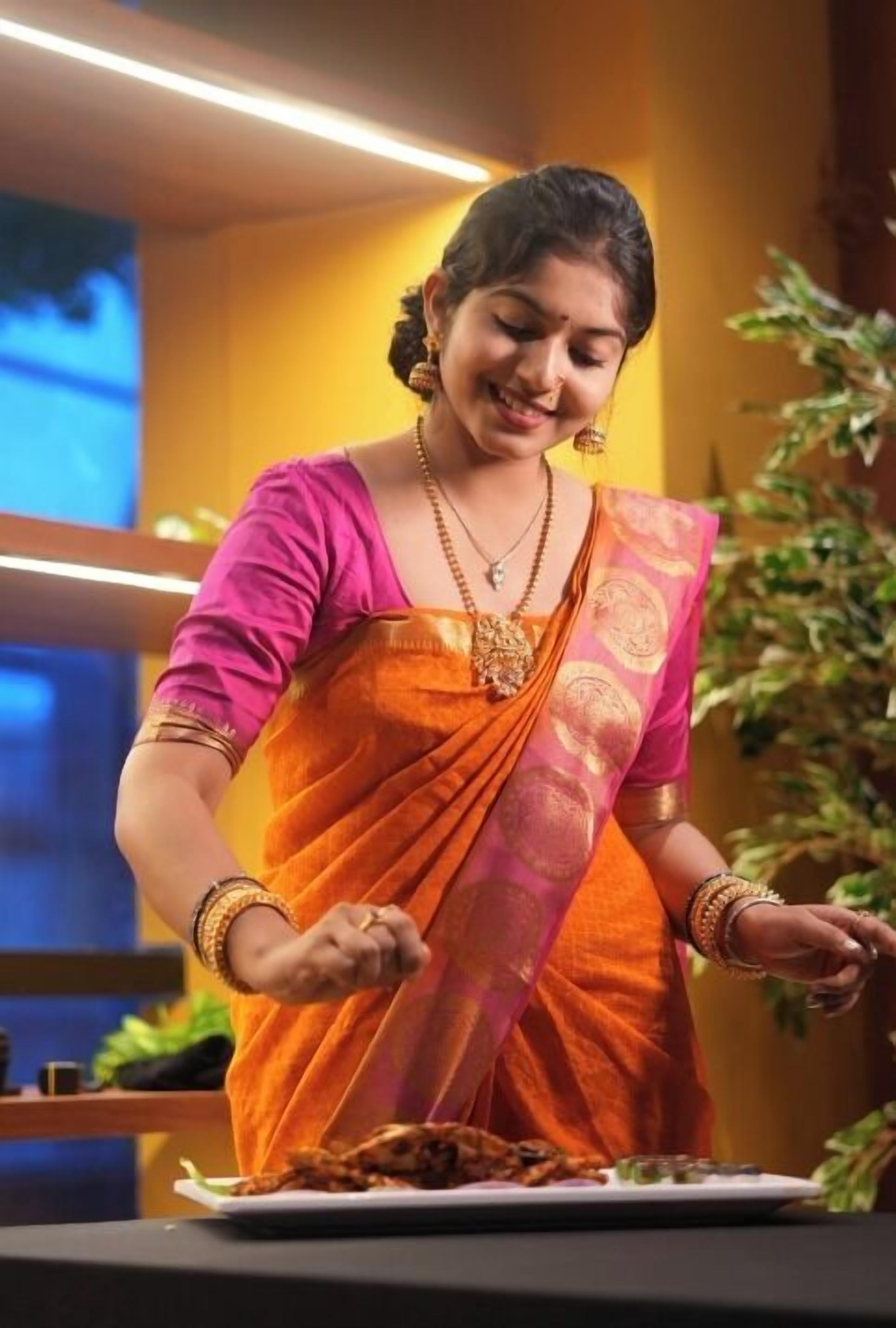 A person in traditional attire serving food on a table.