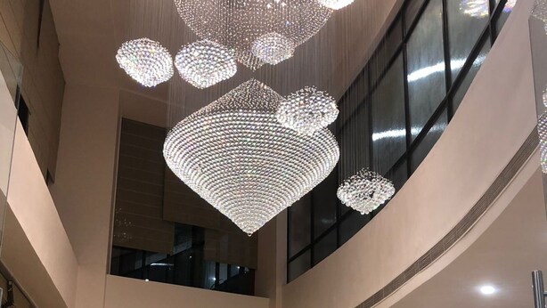 A spacious lobby with a high ceiling, modern chandeliers, and a reception desk. - OASIS SUITES (Hubli)