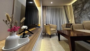 Una sala de estar moderna con un televisor de pantalla plana grande, un sofá, una mesa de centro y un jarrón decorativo con flores.