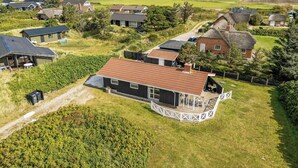 A rural property with multiple houses, a large open field, and a thatched-roof building. - Charming holiday home close to the North Sea and Søndervig center (Ringkøbing)