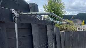 Een houten hek met een metalen poort en een waslijn.