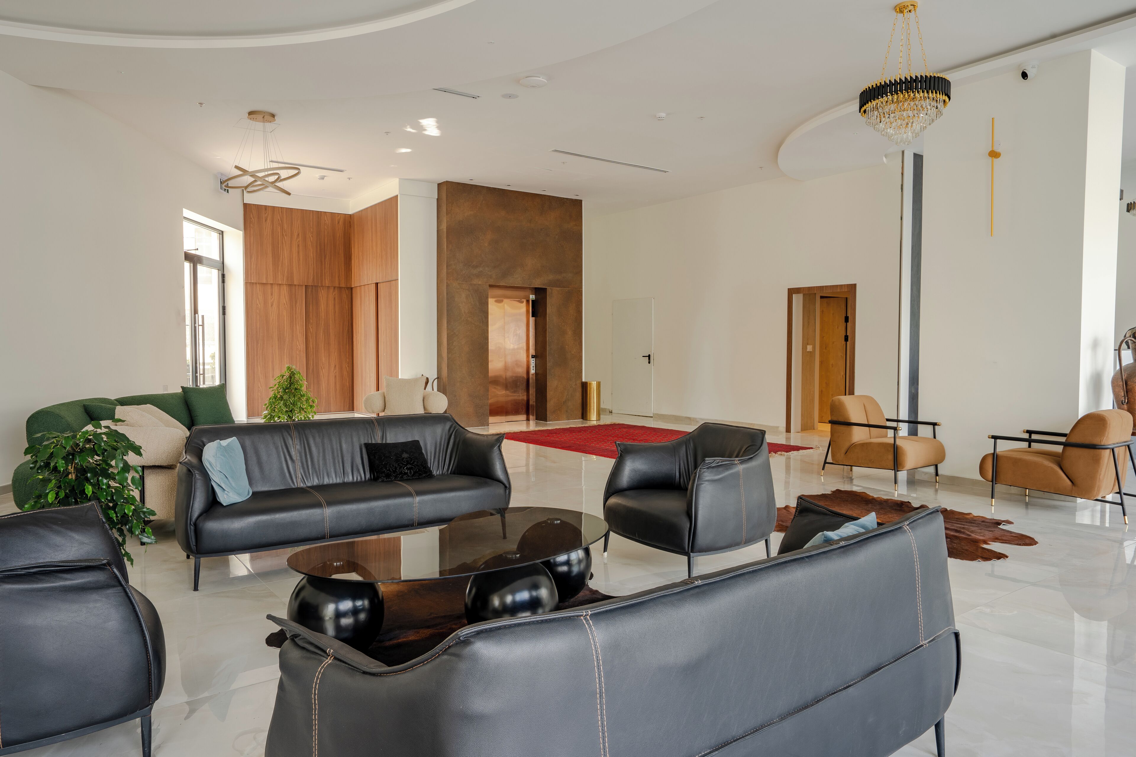 Een moderne woonkamer met leren banken, een glazen salontafel en een kroonluchter.