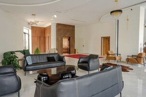 Una sala de estar moderna con sofás de cuero, una mesa de centro de vidrio y una araña.