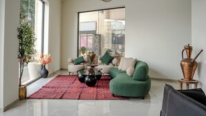 A modern living room with a green sofa, a coffee table, and a large window.