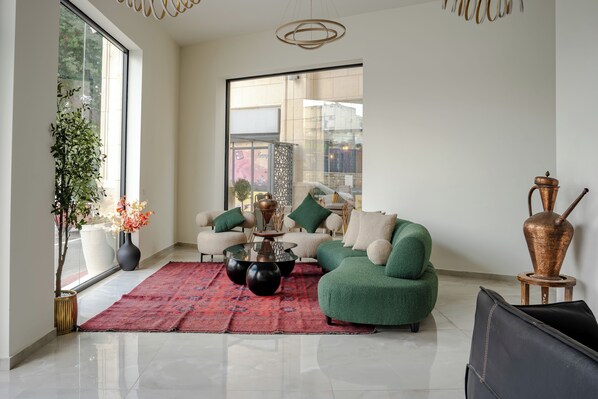 A modern living room with a green sofa, a coffee table, and a large window. - Levant Hotel (Jerusalem)