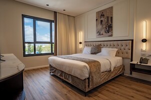 Un dormitorio moderno con una cama grande, una mesita de noche y un ventanal con cortinas.