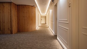 Un couloir avec des lambris en bois d’un côté et des portes blanches de l’autre, qui mène à une pièce au fond.