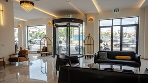 A modern lobby with a revolving door, leather seating, and large windows offering a view of the street.