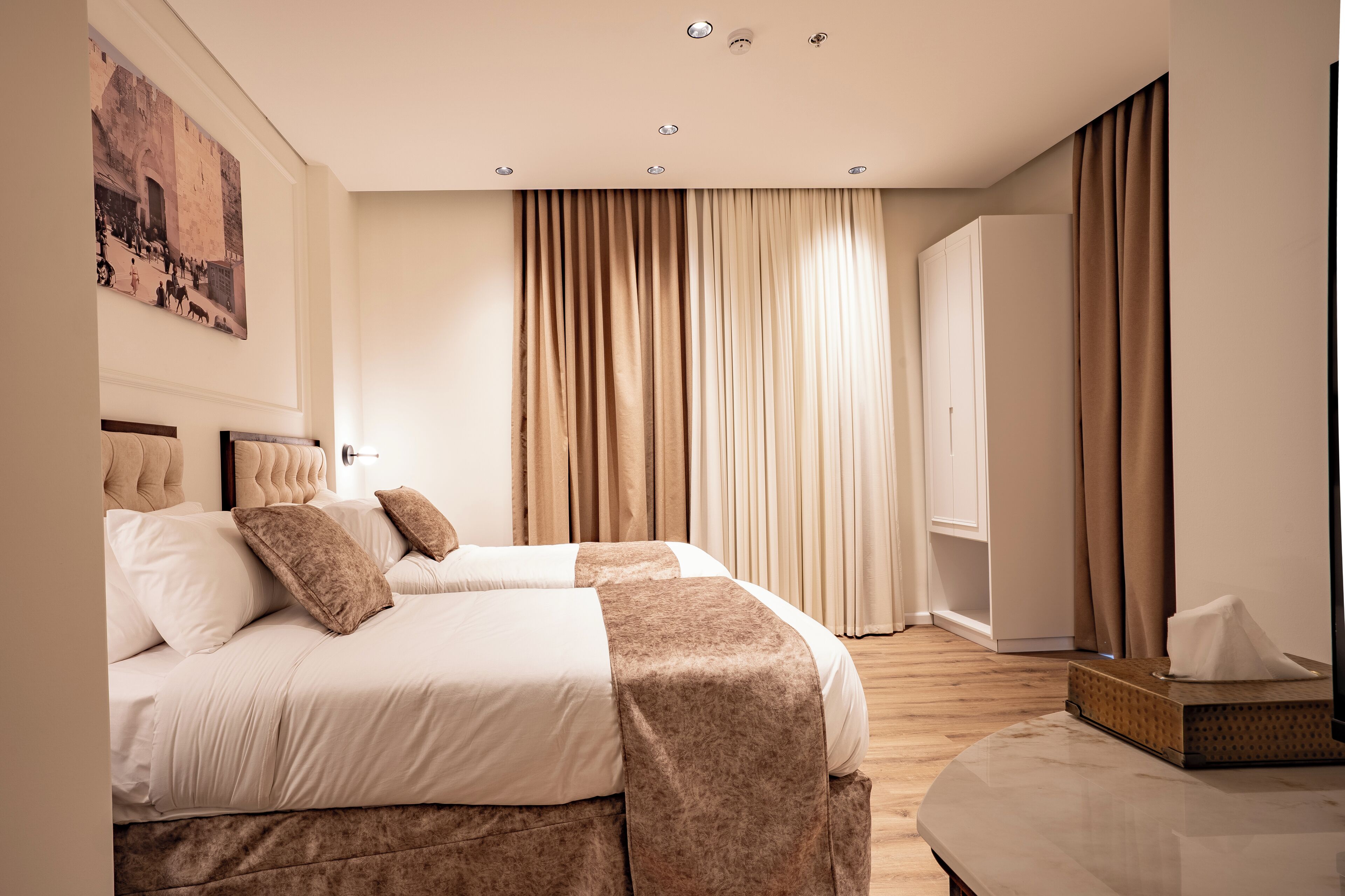 A modern hotel room with a large bed, a bedside table, and a large window with curtains.