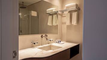 Un baño moderno con un lavabo de mármol, un espejo grande y un perchero para toallas.