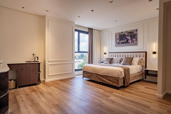A bedroom with a large bed, a desk, and a window with curtains. - Levant Hotel (Jerusalem)