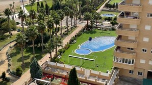A residential building with a rooftop terrace, a swimming pool, and a view of the beach.