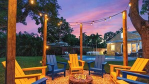 A backyard with a fire pit, outdoor seating, and string lights. - Heated Pool Grill Fire Pit & Cold Plunge Sleeps 8! (West Palm Beach)