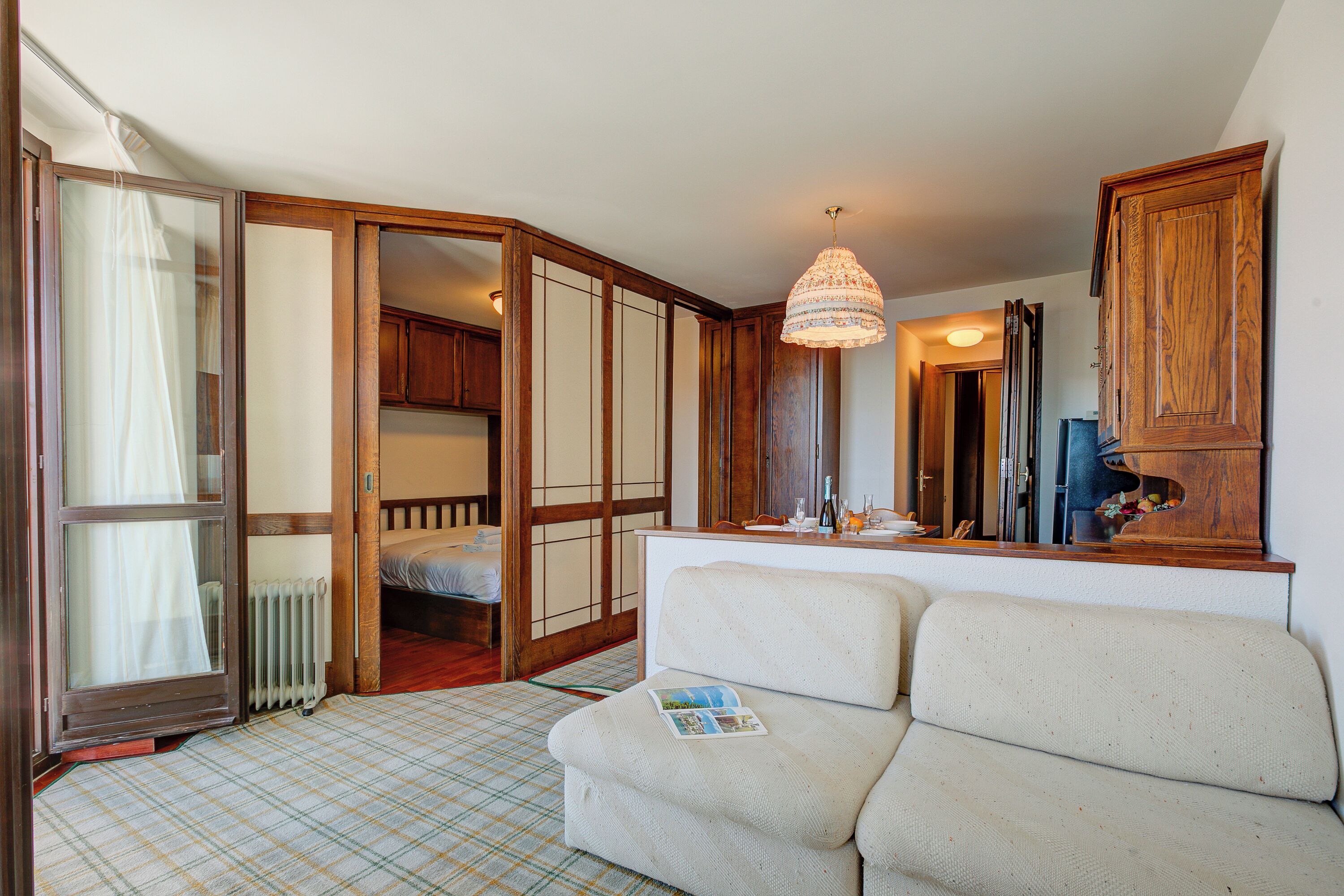 Een kamer met een bank, een houten kast, een spiegel en een bed met raam.