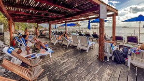 A wooden deck with lounge chairs and umbrellas, overlooking a body of water. - Deluxe Double Room at Casa de los Sueños (Isla Mujeres)