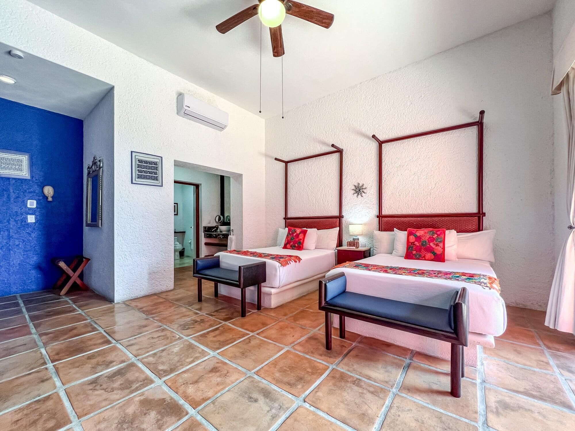 A hotel room with two beds, a ceiling fan, and a bathroom visible through an open door.