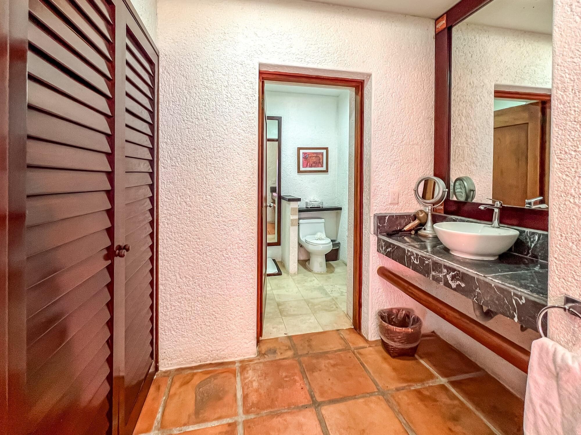 Une salle de bain avec un sol carrelé, un lavabo avec un miroir et des toilettes.