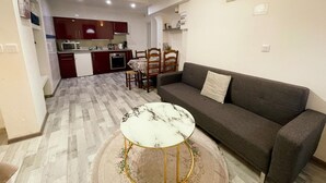 Un espace de vie compact comprenant un coin repas, une kitchenette et un canapé avec une petite table basse ronde.