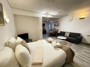A hotel room with a bed, a TV, a sofa, a dining area, and a kitchen in the background. - Studio in Amboise for 2 pers, castle view (Amboise)