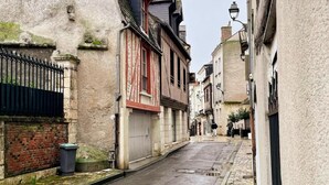 Une rue étroite bordée de vieux bâtiments, une boutique fermée et une clôture en métal.