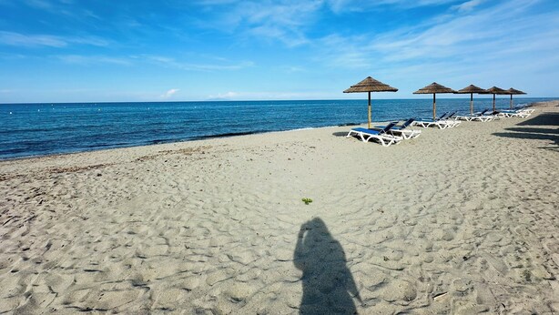 A beach with sun loungers and thatched umbrellas, a clear sky, and calm sea. - - Casa Anna - beachfront (Borgo)