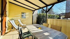 A covered patio with a table and two lounge chairs. - - Casa Anna - beachfront (Borgo)