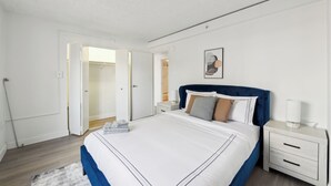 Un dormitorio moderno con una cama grande, una mesita de noche y un armario.