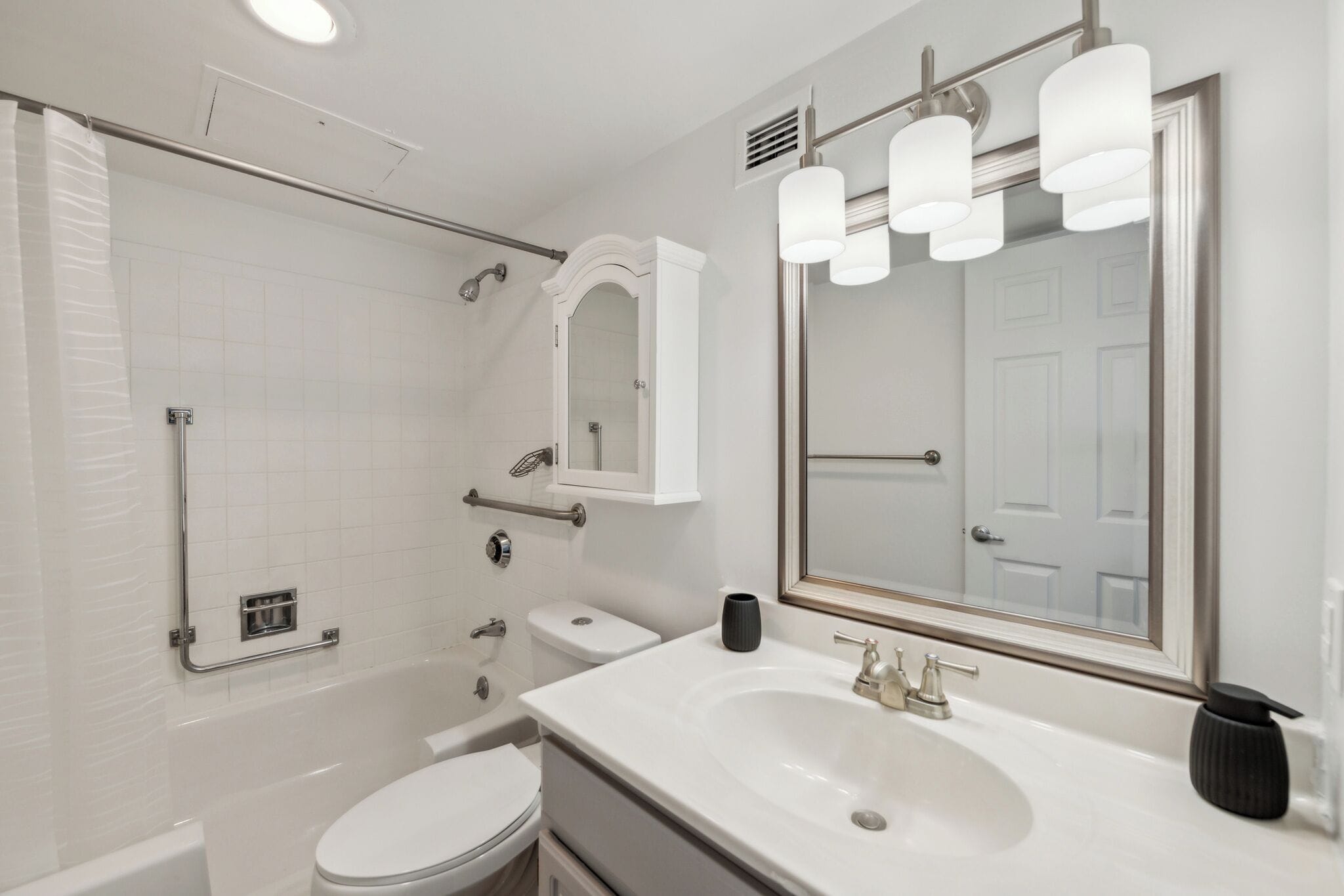 A modern bathroom with a bathtub, toilet, sink, and a large mirror.