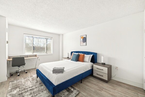 Une chambre moderne avec un lit, un bureau, une chaise et une fenêtre avec des stores.