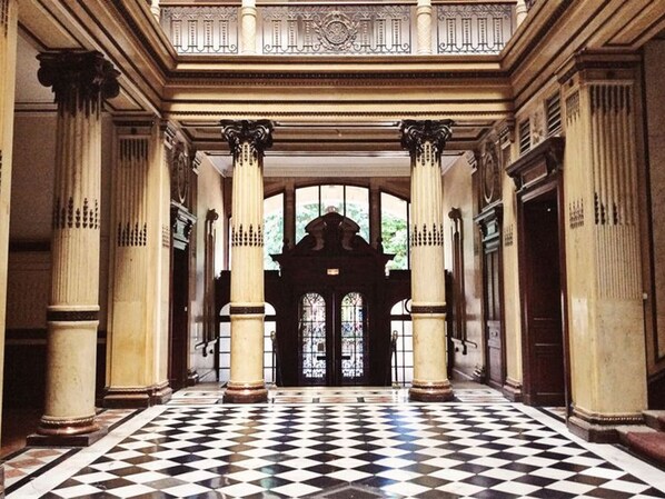 Stately hallway with ornate columns and a grand arched window.