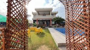 A building with a modern design, a pool, and outdoor seating. - GoBravo 11 6BHK Farm with Pool Sohna Road Gurgaon  (Sohna)