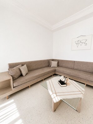 Ein modernes Wohnzimmer mit einem Ecksofa, einem Glastisch und einem Wandbild mit einer Weltkarte.